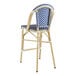A blue and white striped Lancaster Table & Seating counter height outdoor barstool.