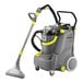 A Karcher Puzzi 30/4 carpet extractor with a grey and yellow machine with a handle.