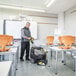 A man using a Karcher walk-behind floor scrubber to clean a room.