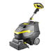 A Karcher walk-behind cylindrical floor scrubber with a handle.