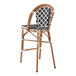 A Lancaster Table & Seating Bistro black and white birdseye weave rattan barstool with a wooden frame.