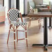 A counter height outdoor side stool with a black and white birdseye weave pattern and rattan frame.