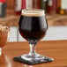 A glass of Cholaca liquid cacao on a wooden table with a coaster.