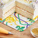A slice of cake with white frosting and yellow, green, and purple sprinkles on a Southern Champion Mardi Gras cake pad.