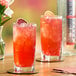 A glass of red SHOTT Energy Boost drink with ice on a table.