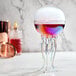 A Flavour Blaster electric jellyfish cocktail glass filled with colorful liquid on a table.