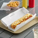 A hot dog in a Southern Champion white paper clamshell container.