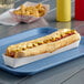 A hot dog with mustard and onions in a white paper footlong hot dog tray.