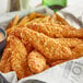 A basket of Brakebush SmartShapes Tater Chip Strip breaded chicken strips and fries.