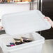 A person using a Vollrath Traex white plastic lid to cover a food container.