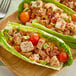 A wooden plate with lettuce wraps filled with Brakebush Farm Pantry boneless skinless halal chicken breast chunks and vegetables.