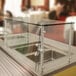 A stainless steel cafeteria food shield with glass top on a counter.