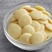 A bowl of Guittard Soie Blanche white chocolate wafers.