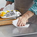 A hand using a WipesPlus table wipe to clean a table surface.