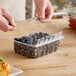 A hand holding a clear plastic clamshell container of blueberries.