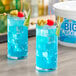 Two blue drinks with pineapple garnish on a table.