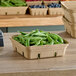 A Choice produce basket filled with green peas on a table.
