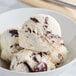 A close up of a bowl of Tillamook Campfire Peanut Butter Cup ice cream with a scoop of white ice cream with brown swirls.