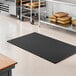 A black heavy-duty rubber anti-fatigue floor mat with a diamond pattern and straight edges, measuring 3 feet by 5 feet.
