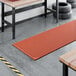 A red heavy-duty rubber anti-fatigue floor mat with a diamond pattern and straight edges, designed to be grease-resistant and used in industrial or workshop settings.