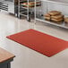 A red heavy-duty rubber anti-fatigue floor mat with a diamond pattern and straight edges, designed for grease resistance.