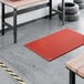 A red heavy-duty rubber anti-fatigue floor mat with a diamond pattern and straight edges, designed to be grease-resistant.