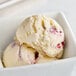 A scoop of Tillamook White Chocolate Raspberry ice cream with red and white swirls in a bowl.