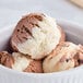 A bowl of Tillamook Udderly Chocolate ice cream with a scoop on top.