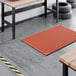 A heavy-duty red rubber anti-fatigue floor mat with a diamond pattern and straight edges, designed to be grease-resistant.