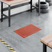 A red heavy-duty rubber anti-fatigue floor mat with a diamond pattern and beveled edge, measuring 2 feet by 3 feet and 1/2 inch thick.