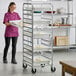 A metal end load rack on wheels holding multiple trays, designed for storing pizza dough boxes.