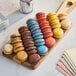 A group of colorful White Toque macarons on a wooden board.