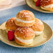 A white plate with White Toque mini Tropezienne pastries topped with raspberries.