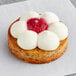 A White Toque cheese and raspberry tartlet with white and pink frosting and a flower on top.