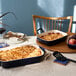 A table with two Staub dark blue rectangular baking dishes and a casserole dish on it.