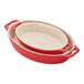 A red ceramic oval baking dish set with handles.