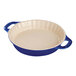 A blue and white ceramic Staub round pan with handles.