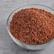 A bowl of Lotus Foods Organic Long Grain Red Rice on a gray surface.