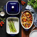 A white and blue Staub baking dish with asparagus and food in it.