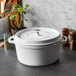 A white Staub enameled cast iron pot with a lid.