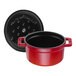 A close-up of a red Staub enameled cast iron pot with a black lid.