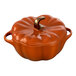 A burnt orange ceramic pumpkin shaped mini casserole dish with a gold stem.