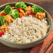 A bowl of Lotus Foods Organic Long Grain White Jasmine Rice with broccoli and peppers.