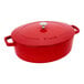 A Staub cherry red enameled cast iron oval Dutch oven with a lid.