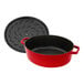 A red Staub enameled cast iron oval Dutch oven with a lid.