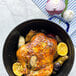 A Staub dark blue enameled cast iron pot with a chicken and vegetables in it.