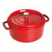 A Staub cherry red enameled cast iron pot with a lid.