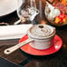 A Staub graphite gray mini enameled cast iron sauce pan with lid on a plate.