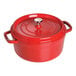 A Staub cherry red enameled cast iron pot with a lid.