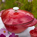 A Staub cherry red enameled cast iron heart-shaped pot with a lid.
